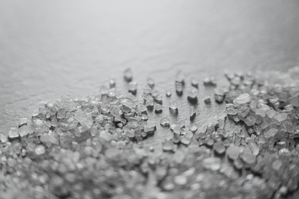 Detailed macro shot of scattered rock salt crystals with soft focus, creating a textured abstract pattern.